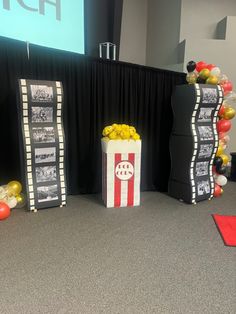 popcorn buckets with movie film strips and balloons in front of a stage set for an event