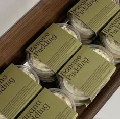 six jars of food sitting on top of a wooden box with labels in them that say, ground pudding