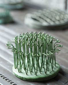 a green hair comb sitting on top of a wooden table next to other metal objects