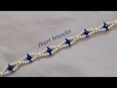 a bracelet with pearls and blue stars is shown on a white sheet that says pearl braclet