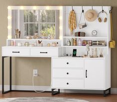 a white desk topped with lots of drawers under a window next to a wall mounted mirror