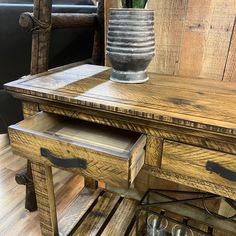 an old wooden table with two drawers and wine glasses on it next to a chair