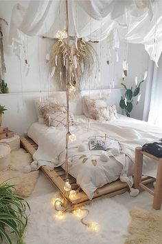 a bed with white sheets and lights hanging from the ceiling