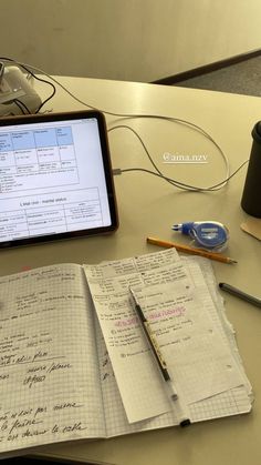 an open notebook sitting on top of a desk next to a computer monitor and pen