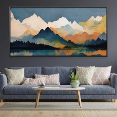 a living room with a couch, table and painting on the wall above it that has mountains in the background