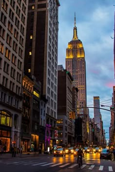 a city street filled with lots of traffic and tall buildings in the background at night