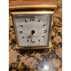 an alarm clock sitting on top of a counter next to a marble countertop with gold trim