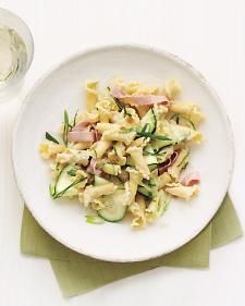 a white plate topped with pasta and veggies next to a glass of water