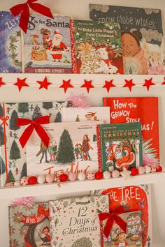 several christmas books are hanging on the wall with red bows and ribbons around them, along with other children's books