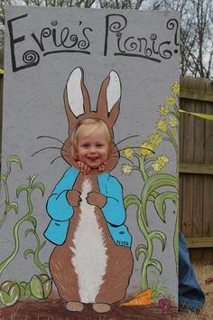 a young child standing in front of a sign with an image of a rabbit on it