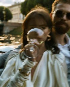 a man and woman sitting next to each other while holding wine glasses in their hands