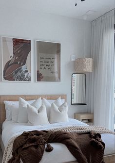 a bed with white sheets and pillows in a bedroom next to two pictures on the wall