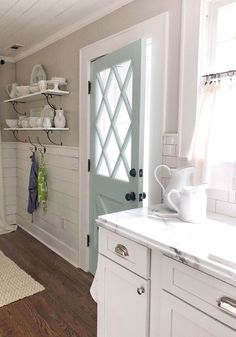 a kitchen with white cabinets and open shelves next to a door that leads to the outside