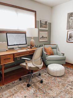 a home office with a chair, desk and computer on top of a rug in front of a window