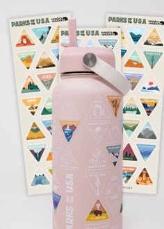 a pink water bottle sitting in front of a white wall with stickers on it