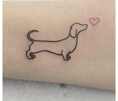 a small black dog with a heart on it's back side arm tattoo design