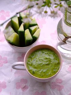 a bowl of cucumbers and a cup of water on a floral tablecloth