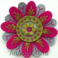 a pink and green flower brooch sitting on top of a white surface