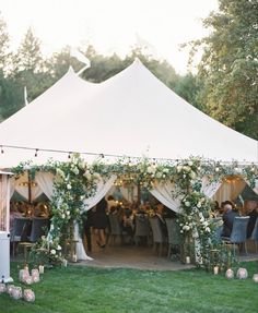 an outdoor tent with white flowers and greenery