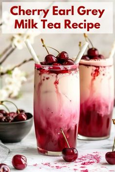 two glasses filled with cherries and milkshakes on top of a white table