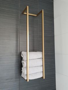 a towel rack in the corner of a bathroom with towels hanging on it's sides