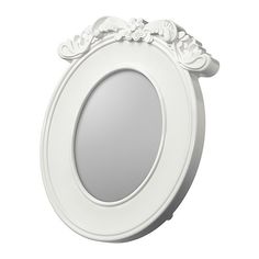 an oval white mirror with flowers and leaves on the edge, hanging from a wall