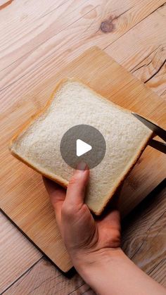 a person cutting bread on top of a wooden cutting board