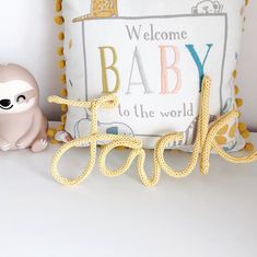 a stuffed animal sitting next to a welcome baby sign and pillow on a white table