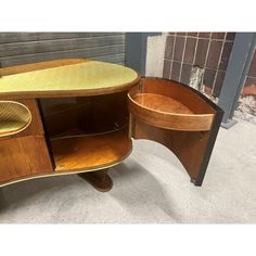 an old fashioned wooden desk with two drawers and a shelf on the bottom, in front of a brick wall