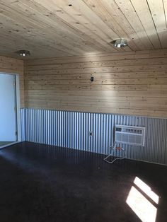 an empty room with wood paneling on the walls and floor, in front of a door