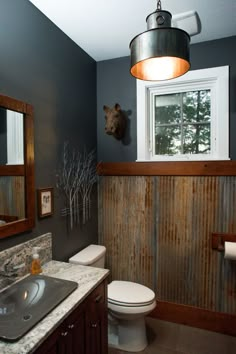 a bathroom with a toilet, sink and mirror in it's corner next to a window