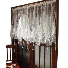 an old fashioned window with white lace on the top and bottom, next to a rocking chair