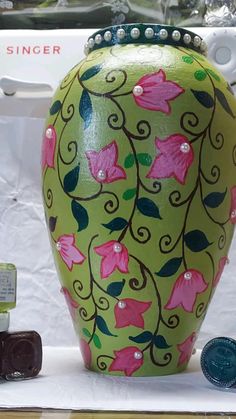 a green vase with pink flowers painted on it