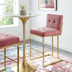 two pink chairs sitting next to each other in front of a table with a potted plant on it