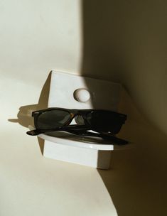 a pair of black sunglasses sitting on top of a white shelf next to a wall