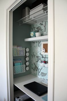 an open closet door with shelves and items on the shelf in front of it, including a laptop computer