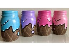 three jars with ice cream on them are lined up against a white wall, one has chocolate and the other is pink