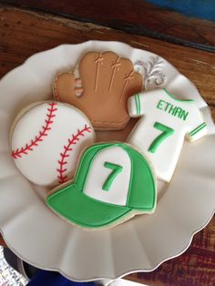 decorated cookies in the shape of baseballs, mitts and jersey on a plate