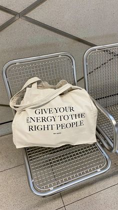 two metal chairs with a tote bag sitting on top of one that says give your energy to the right people