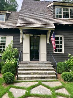 a gray house with an american flag on the front door and steps leading up to it