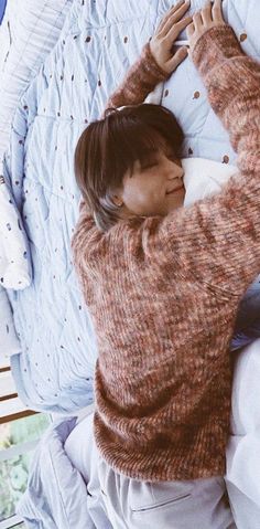 a woman laying on top of a bed next to pillows