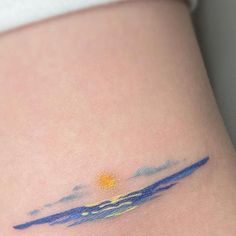 a small tattoo on the side of a woman's stomach that is painted with blue and yellow watercolors