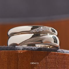 three wedding rings sitting on top of each other in a wooden box with the word diaco written below them