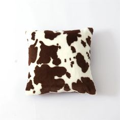 a brown and white cow print pillow on a white background