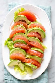 a white plate topped with slices of watermelon and avocado on lettuce