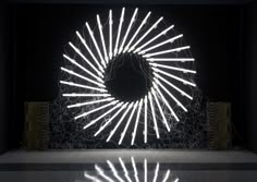 an artistic sculpture made out of lights in a dark room with shadows on the floor