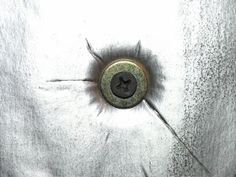 a button that is on the side of a white cloth covered wall with holes in it