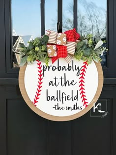 a baseball wreath is hanging on the front door with ribbon and ribbons around it that says probably at the ballfield, the smiths