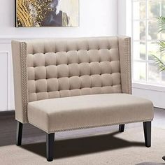 a beige chair sitting on top of a rug in front of a white wall and window