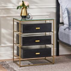 a black and gold three drawer nightstand with flowers on the side table next to it